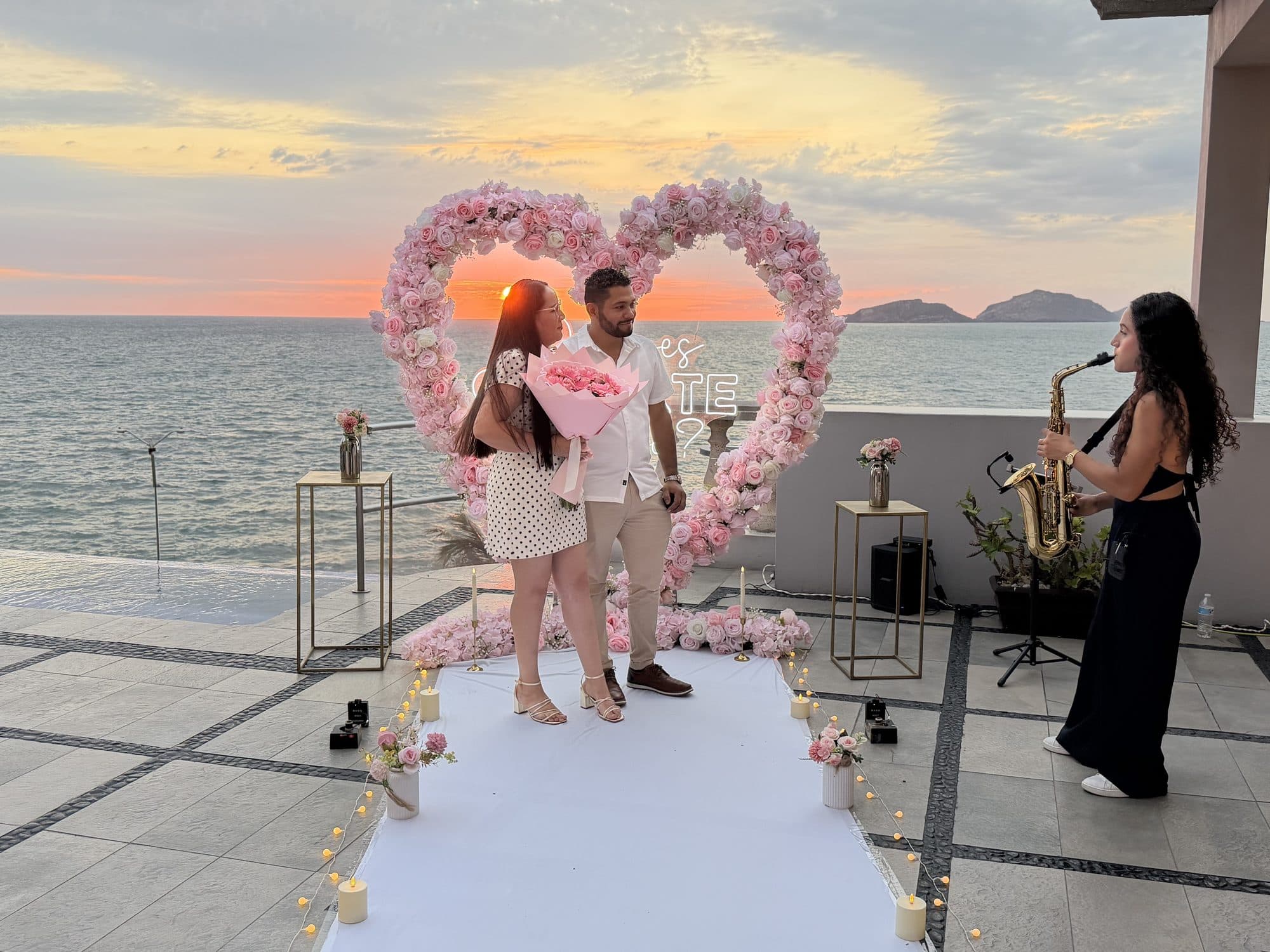 Pareja celebrando en terraza frente al mar con música en vivo